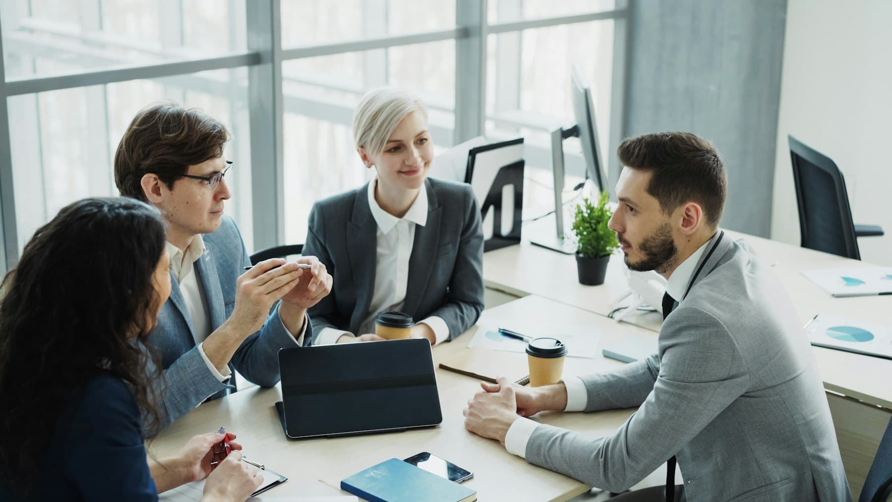 Ett B2B-team i ett ljust mötesrum diskuterar ett beslutsunderlag.